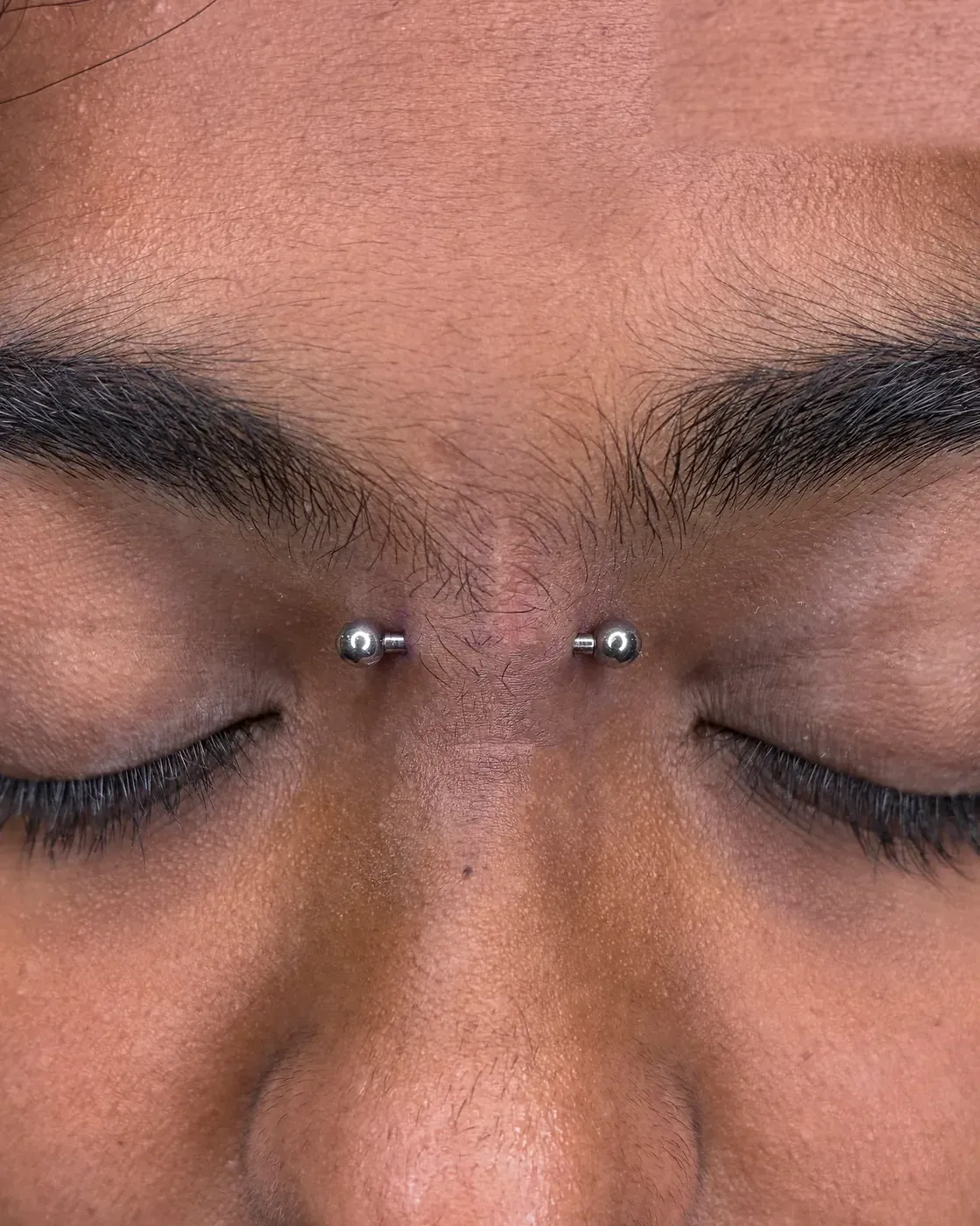 Bridge barbell piercing in implant grade titanium across the nose bridge at Rebel Tattoos Gurgaon