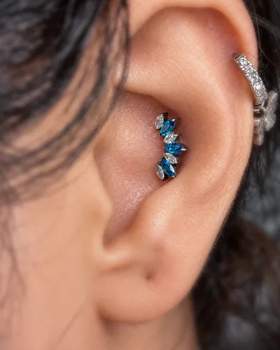 Conch piercing with a blue marquise cluster in implant-grade titanium at Rebel Tattoos Gurgaon