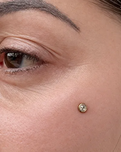 Cheekbone dermal piercing with an implant-grade titanium anchor at Rebel Tattoos Gurgaon