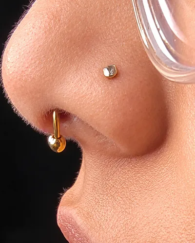 Double nostril piercing with a stud and a hoop in implant-grade titanium at Rebel Tattoos Gurgaon