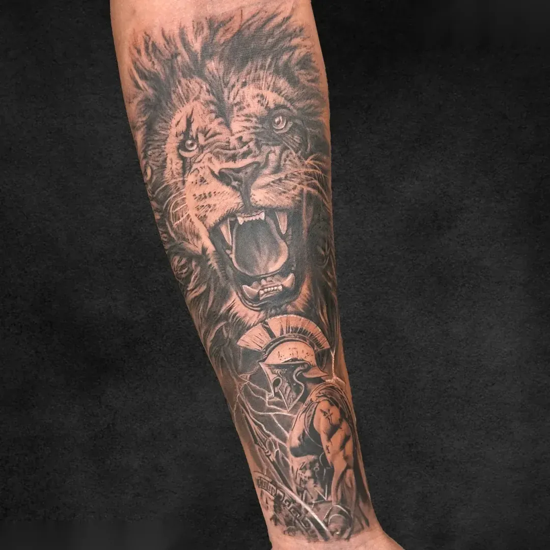 Lion and Spartan warrior black and grey realism forearm tattoo at Rebel Tattoos Gurgaon