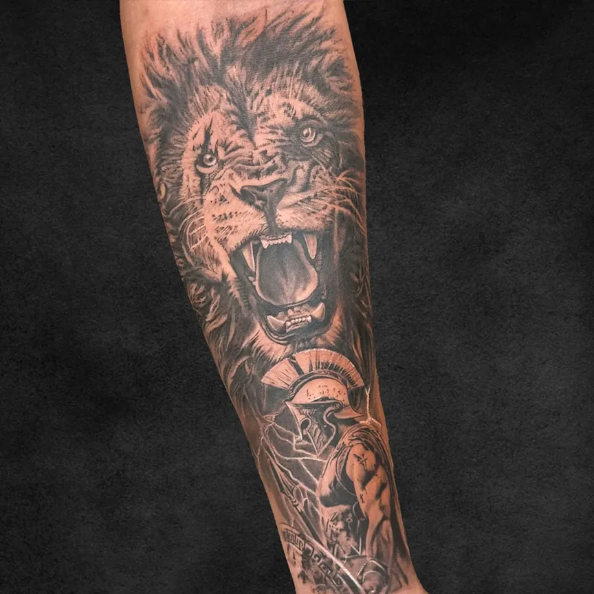 Lion and Spartan warrior black and grey realism forearm tattoo at Rebel Tattoos Gurgaon